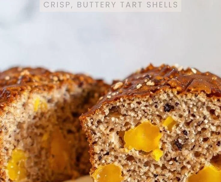 Sliced easy mango bread with pieces of mango on a wooden table