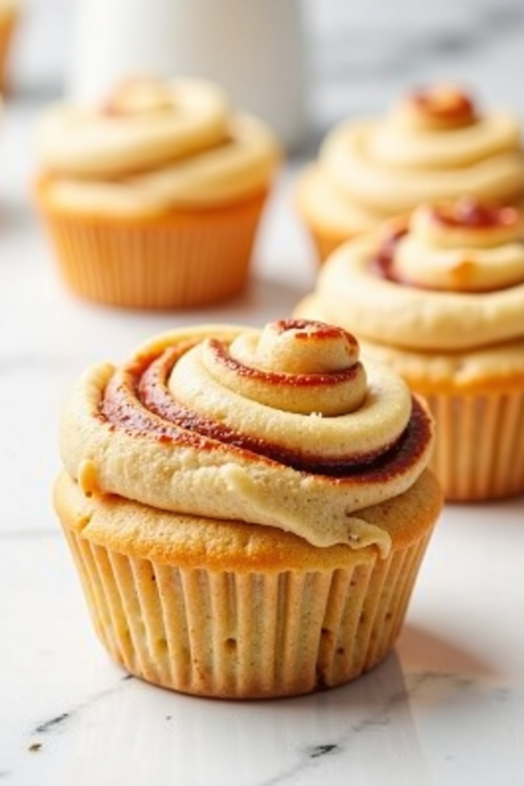 Fluffy cinnamon roll muffins on white marble, bright natural light
